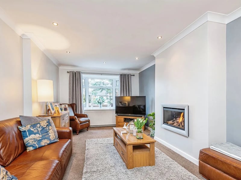 A spacious living room with fireplace and large bay window.