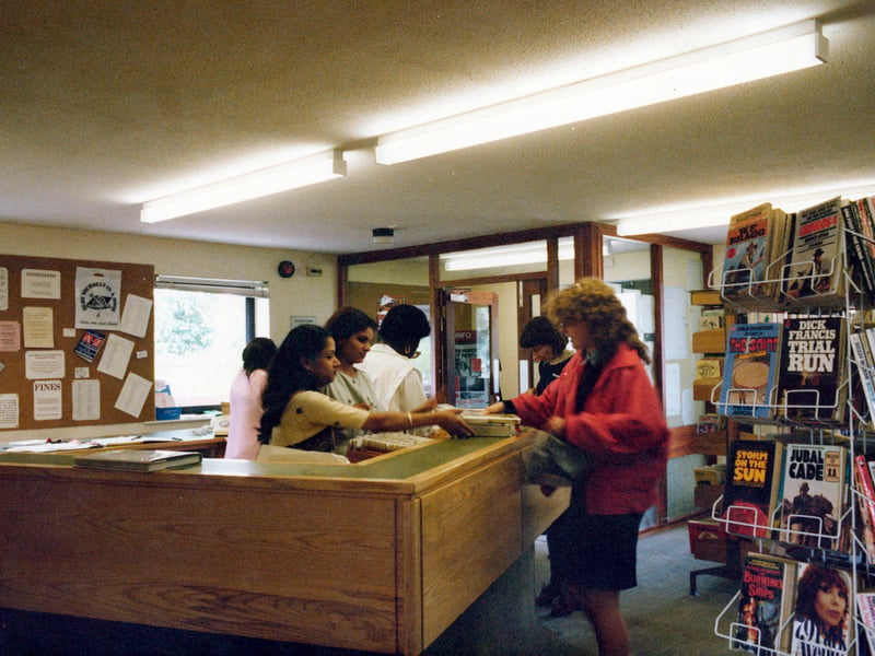 Inside Chapeltown Branch Library on Reginald Terrace in June 1985. The counter area is on the left while in the foreground on the right is a stand of paperback books.
