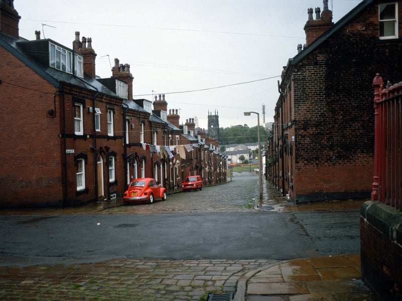 Looking south down Quarry Street past the junction with Cross Quarry Street in the foreground. A fence on the right encloses the grounds of Quarry Mount Primary School. St. Mark's C. of E. Church is seen in the background. Pictured in August 1985.
