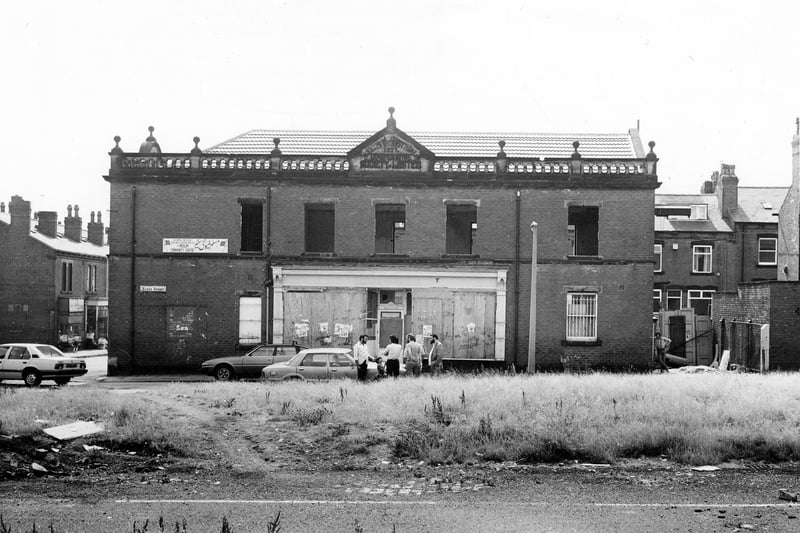 the front view of the former Leeds Industrial Co-operative Society Building at number 1 Hardy Street. A decorative gable on the roof has a datestone of 1897. The view looks across to Hardy Street over waste land where Ellis Place once stood, a short street of red brick terraced houses. At the time of the photograph in July 1984 the old co-op was being converted to the Kashmir Muslim Welfare centre to include a mosque.