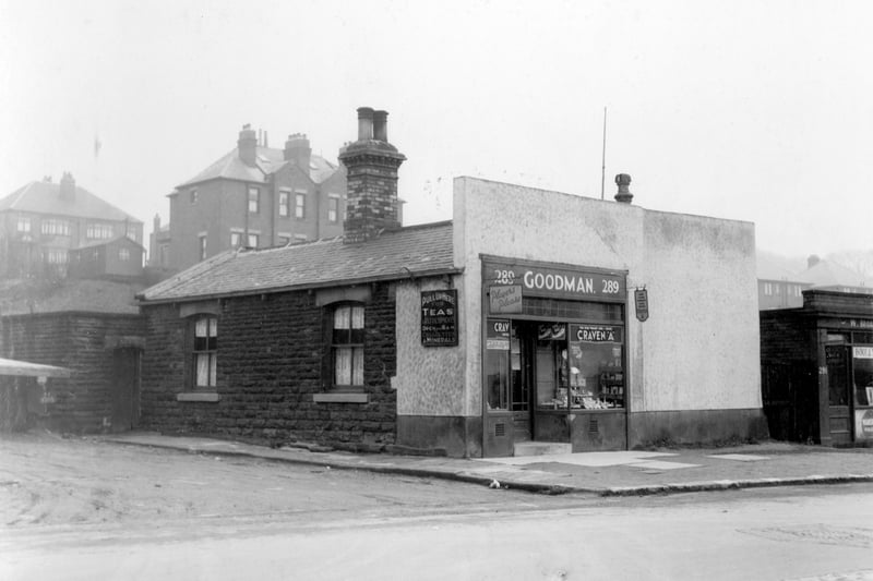  Goodman's Cafe on Stanningley Road in March 1939. A sign on the wall states 'Pull up here for teas and refreshments, Open 6am'. There is a parking area on the left side. Number 291 on the right is a boot repair shop. Behind are semi-detached houses on Green Hill Road. The area in the foreground is now occupied by modern detached houses dating from the 1970s.