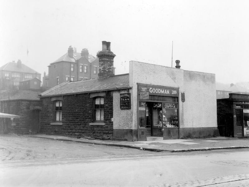  Goodman's Cafe on Stanningley Road in March 1939. A sign on the wall states 'Pull up here for teas and refreshments, Open 6am'. There is a parking area on the left side. Number 291 on the right is a boot repair shop. Behind are semi-detached houses on Green Hill Road. The area in the foreground is now occupied by modern detached houses dating from the 1970s.