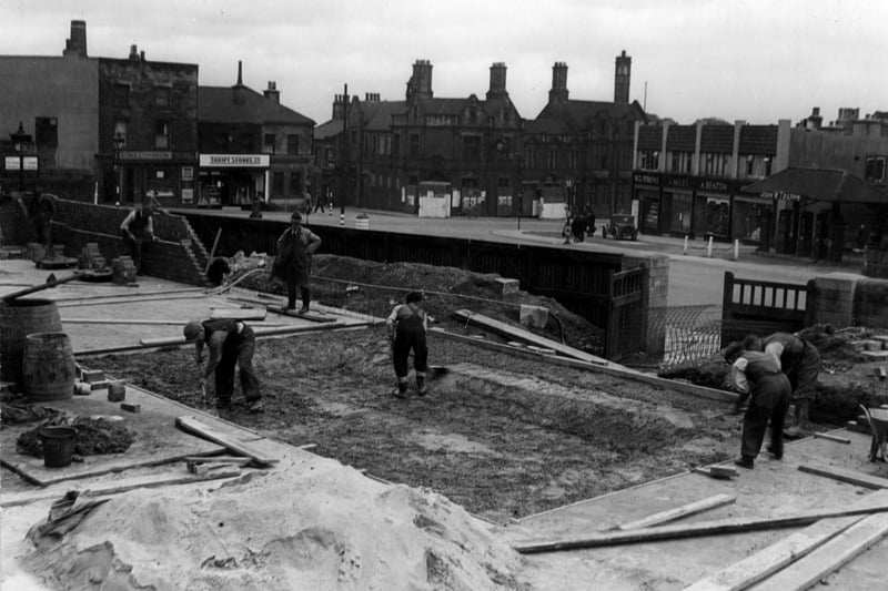 Construction of a static water supply basin in the grounds of Allerton House on the corner of Stainbeck Lane, digging and bricklaying in progress on the wartime project. The photo shows Stonegate Corner with number 2 Perkins Confectioners, J Miles number 4, A Bentons's shoe shop and Trapps petrol station. On Harrogate Road is the public library and police station, with the Midland Bank, Thrift Stores and George Stephenson, butchers, on the other side of Town Street. Pictured in July 1942.