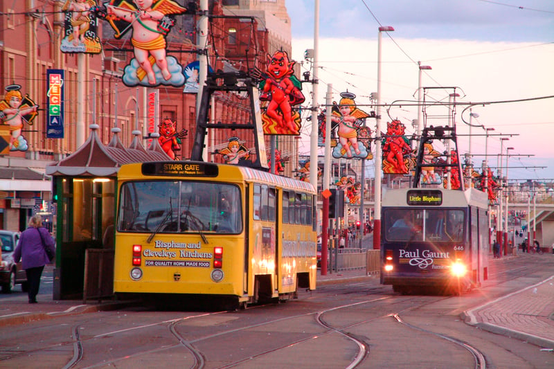 Blackpool seafront, adorned with decorations for the illuminations adorning the lamp posts and other structures, as a brace of the resort's famous heritage trams pass each other, 2004
