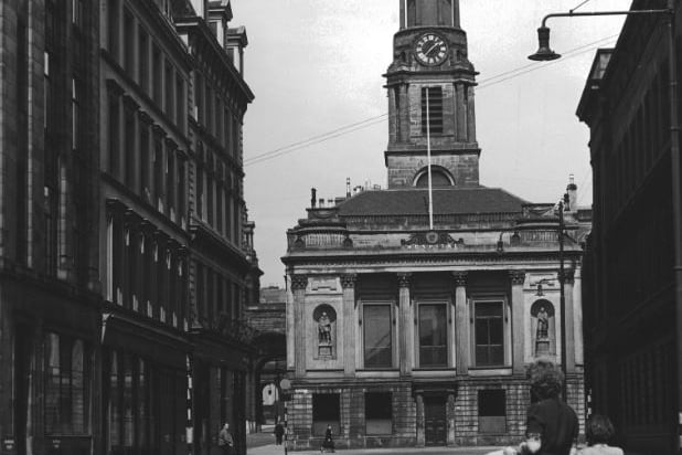 Hutchesons' Hall, or Hospital, on Ingram Street, looking north along Hutcheson Street in 1955. The original Hutchesons' Hospital was demolished in 1795 to make way for the laying out of Hutcheson Street. The building depicted here was designed by David Hamilton and completed in 1805 at the head of the new street. The distinctive octagonal spire is adorned with a clock and dial plate and stands 150 feet tall.