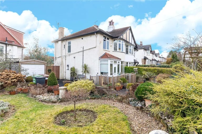 The south-facing garden features pebbled paths, lawns and mature shrubs and trees.