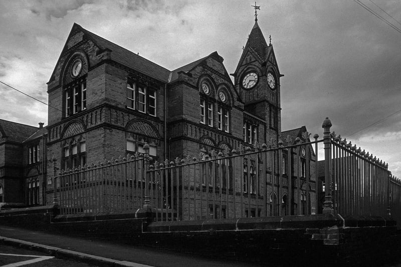 Quarry Mount Primary School seen from Pennington Street by the junction with Cross Quarry Street, right, in August 1985. Built in 1885 as a Board School, it was designed in a Gothic Revival style by Richard Adams, the School Board's architect. The red brick building features a clock tower as its centrepiece. It was one of the last designs by Richard Adams who had been the School Board's architect since 1873. 