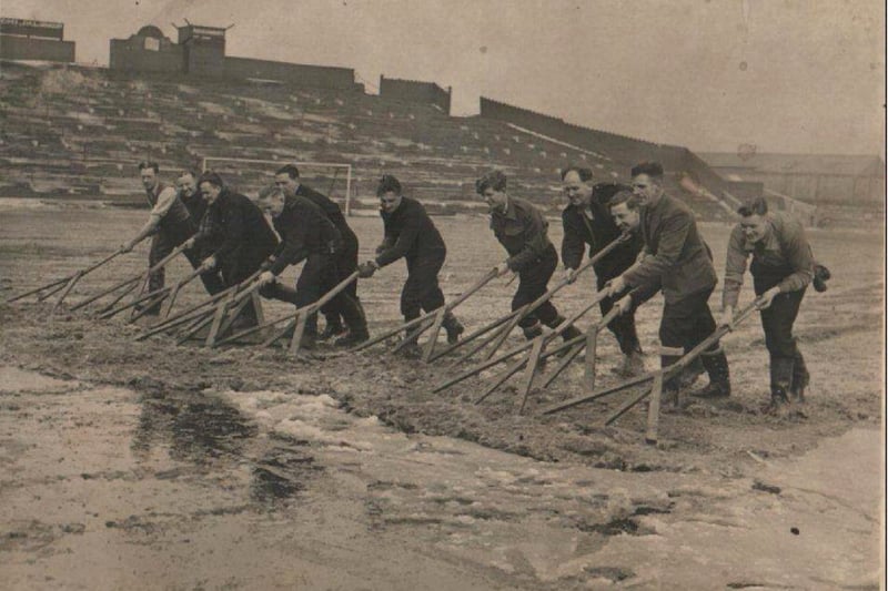Off duty firemen help clearing snow from the pitch at Bloomfield Road football ground prior to the cup tie