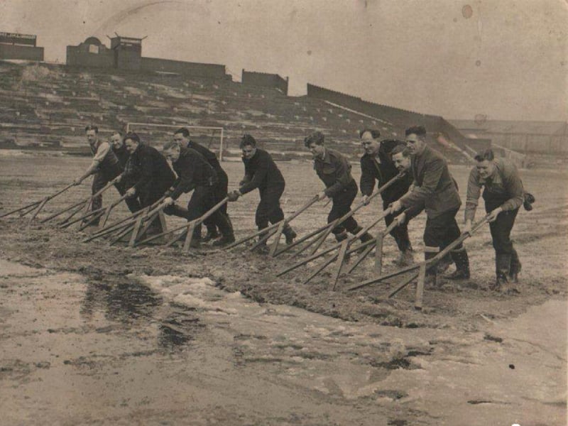 Off duty firemen help clearing snow from the pitch at Bloomfield Road football ground prior to the cup tie