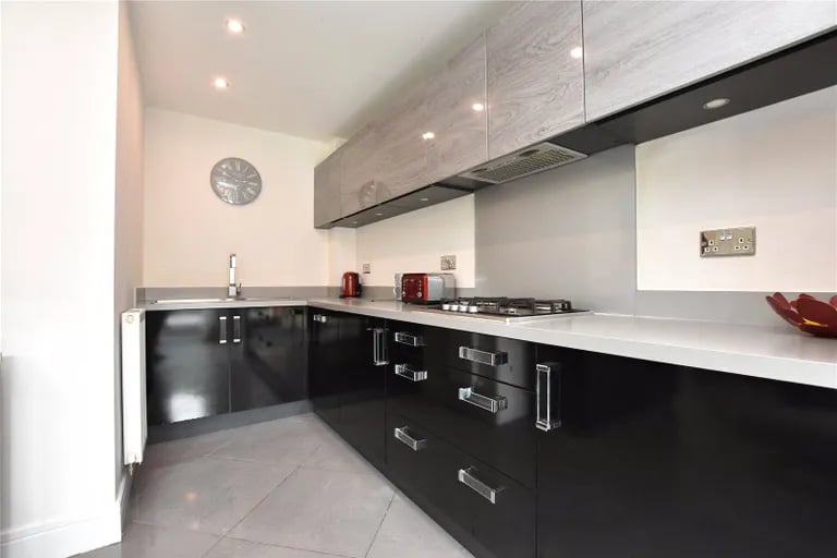The kitchen has a range of fitted wall and base units with complementary work surfaces over.