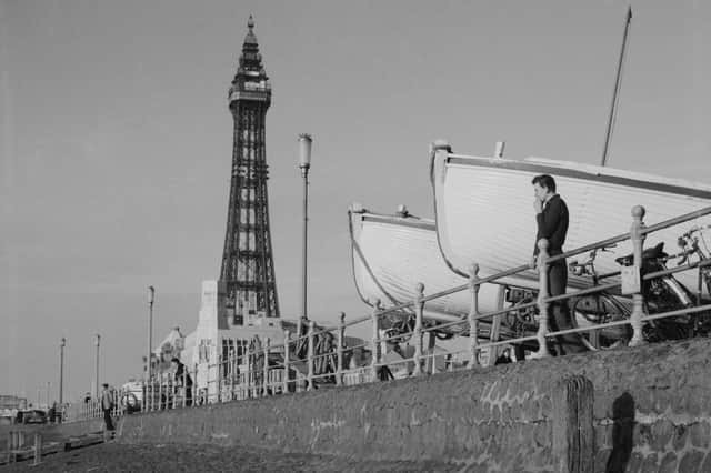 Man standing looking out over the beach in front of Blackpool Tower next to two large boats supported on carriages, 1950 (Photo by The Montifraulo Collection/Getty Images)
