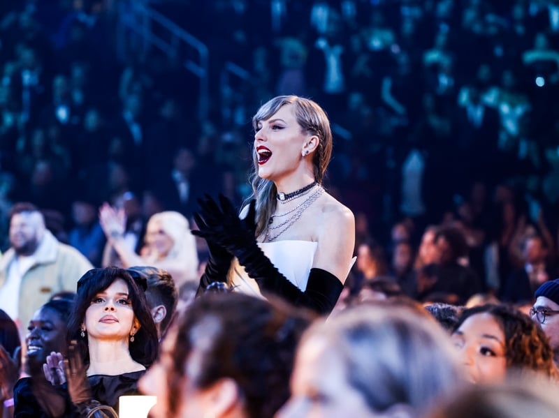 Taylor Swift stands up and cheers during the Grammy Awards. 