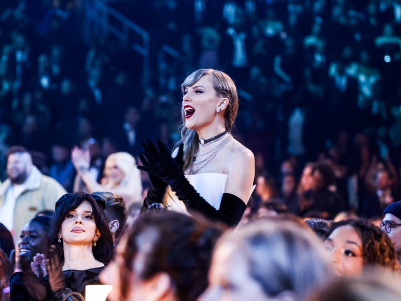 Taylor Swift stands up and cheers during the Grammy Awards.