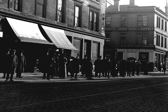 A busy tram stop on either Dumbarton Road or Peel Street in the early 20th century