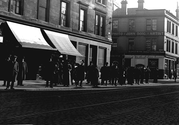 A busy tram stop on either Dumbarton Road or Peel Street in the early 20th century