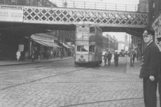 A traffic official keeps an eye on Dumbarton Road as the tram passes.