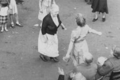 A pair of women dance and children look on during a party in a back court in Partick