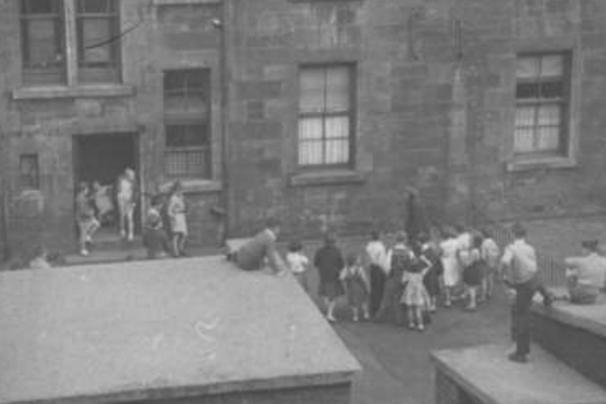 A group of kids play around the wash-house in a Partick back court