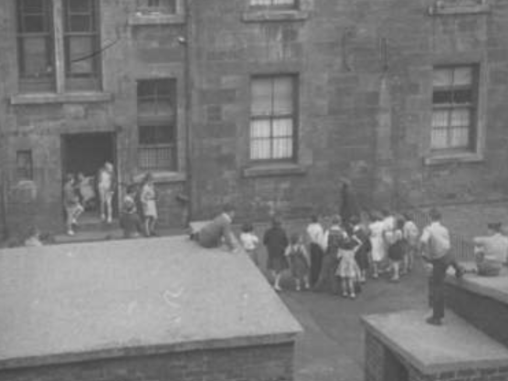 A group of kids play around the wash-house in a Partick back court