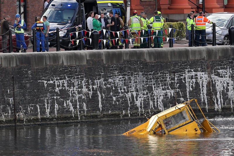 An almost completely submerged Duck Bus in the Albert Dock on June 15, 2013 as rescue workers and members of the public stand on the dockside. 