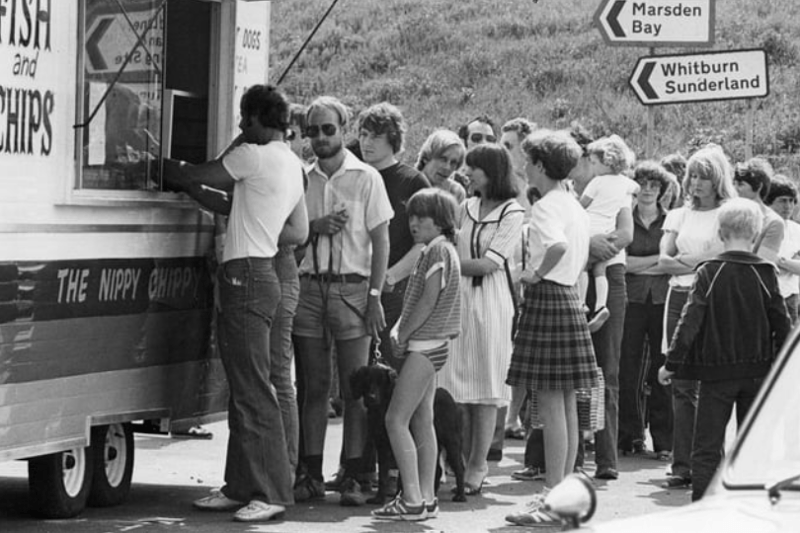 Hungry beach-goers buy fish and chips at South Shields sea front in July 1982. Can you spot a familiar face? 