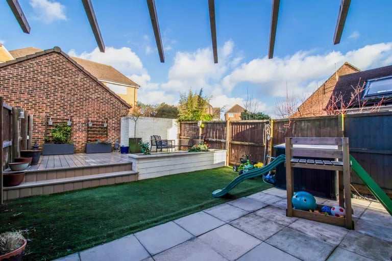 The rear garden features artificial grass, patio and raised decked area.