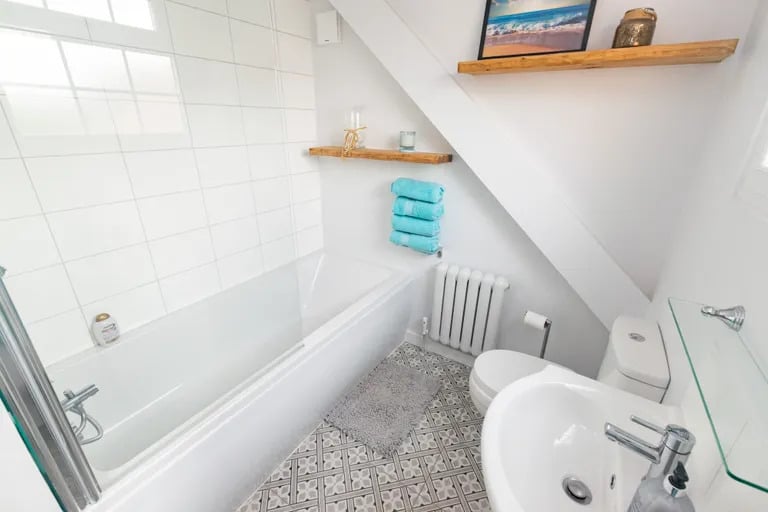 The home has a guest WC and this contemporary house bathroom with bathtub and shower over.