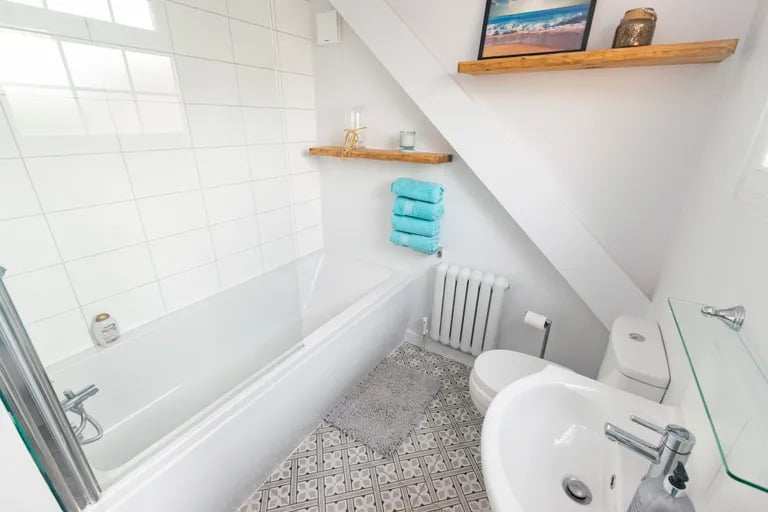 The home has a guest WC and this contemporary house bathroom with bathtub and shower over.