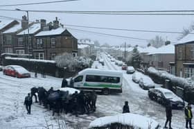 Students help a driver stuck in the snow at the top of Granville Road, in the Norfolk Park area of Sheffield, on Thursday, February 8