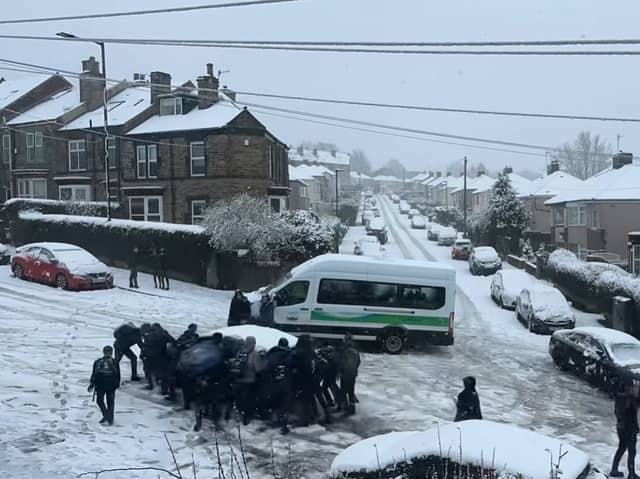Students help a driver stuck in the snow at the top of Granville Road, in the Norfolk Park area of Sheffield, on Thursday, February 8