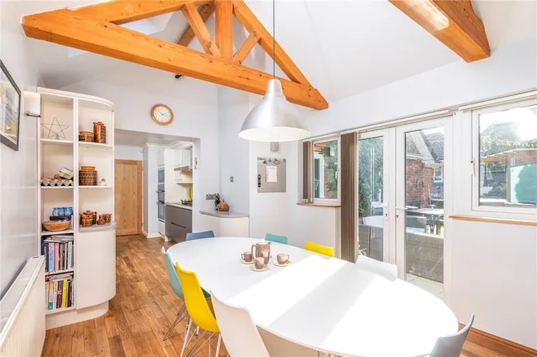 It leads to this bright dining room with exposed beams and access to the patio.