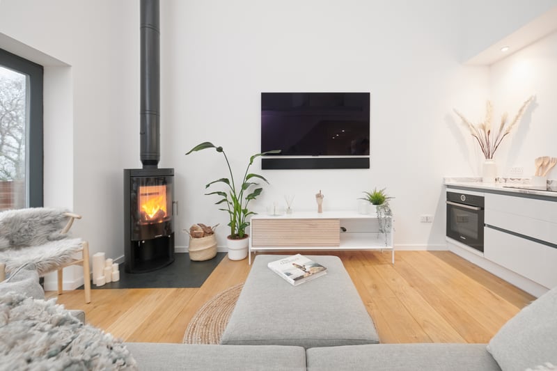 The open plan living and kitchen space has a TV and a log-burner.