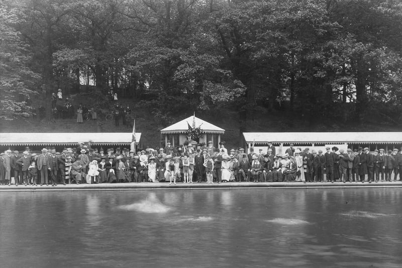 The official opening ceremony for Roundhay Park open air swimming pool in June 1907.. Guests dressed in the fashion of the period are seated on standing round the pool, with more behind on the embankment. A lone swimmer is testing the water.