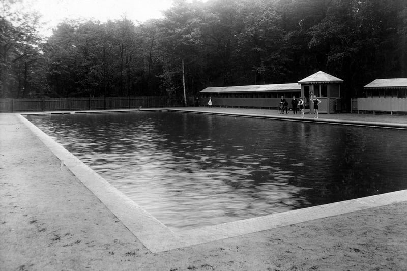 The open-air swimming baths. Changing cubicles visible on the right, bathers and onlookers can be seen. These public baths were opened on June 19, 1907 at a cost £1,657 and were built by the unemployed.