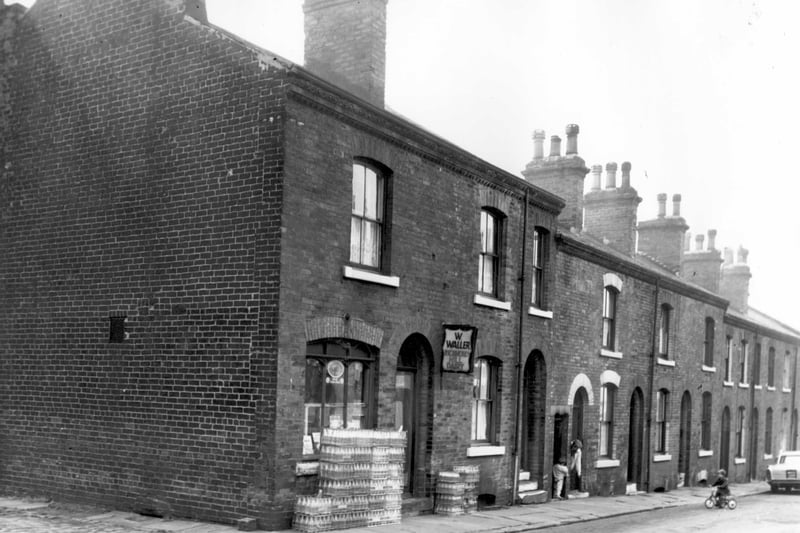 On the left is the entrance to Butterfield Place. Number 16 Butterfield Street is a dairy, the business of Walter Waller. There is a sign outside 'Richmond Hill Dairy'. Crates of milk bottles are stacked outside. Pictured in October 1963.