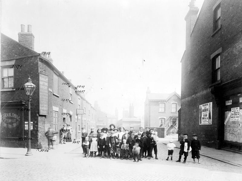 Taken from Waterloo Road, looking down Bower Row prior to the Waterloo Road improvements. On the right is an empty unidentified retail premises, next to this is a large poster advertising Taylor's Drug Co. Further down the street is a house called Claremont House which has wooden carts in the yard. Towards the rear of the street, which is a cul-de-sac, it is possible to see the rear of the Grey Mare Inn which is located on Low Road beyond. Pictured in August 1904.