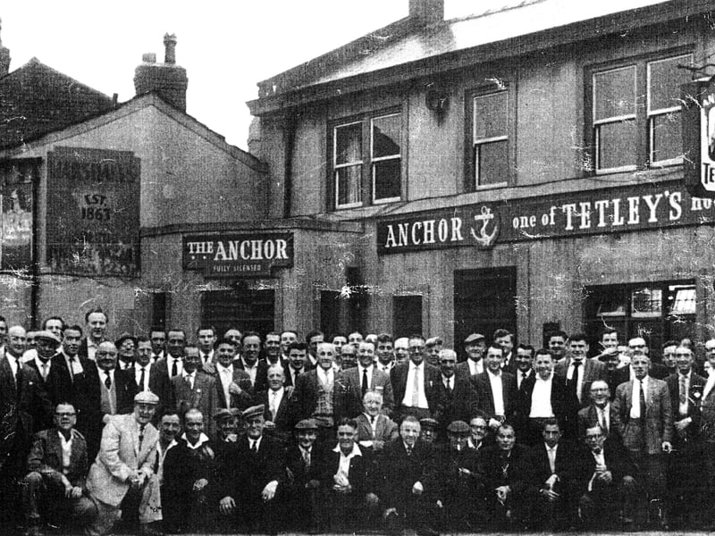A large group of men gathered together outside the Anchor Inn on Church Street in the early 1960s. Many are smiling as they are about to embark on their annual trip to Blackpool. 