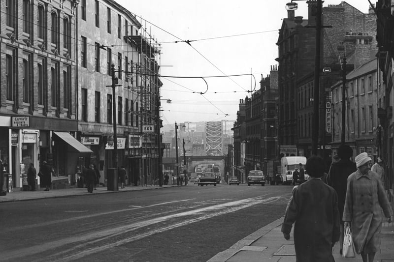 A view of pilgrim Street looking south towards the Tyne Bridge. Tram wires can be seen overhead. Lunn's Holiday travel shop is pictured on the left of the photograph. Tower blocks in Gateshead can be seen over the bridge