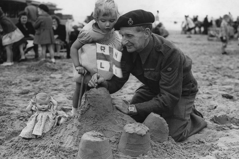 26th June 1943:  A staff sergeant making sand castles for his granddaughter, on Blackpool beach, whilst on leave.  (Photo by George W. Hales/Fox Photos/Getty Images)