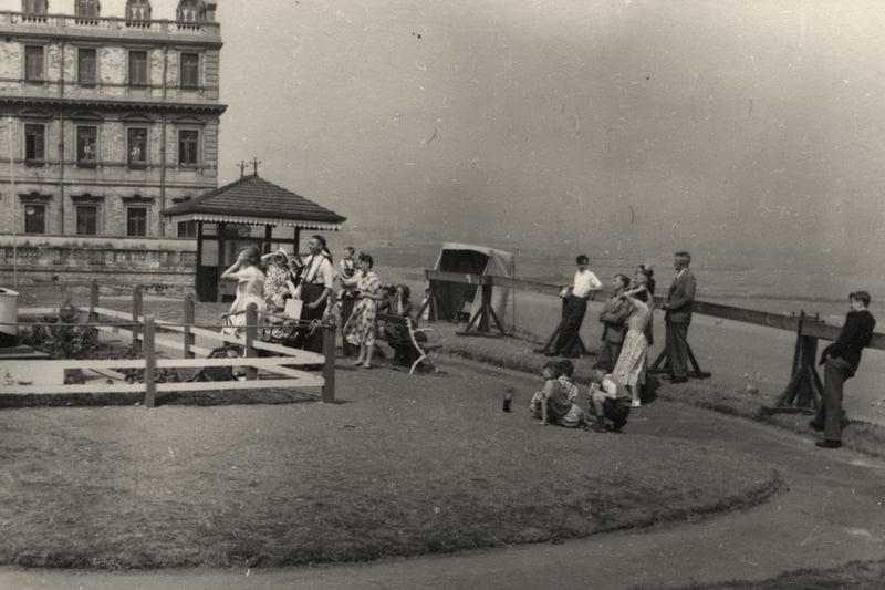 People standing on cliff top. The building in the background is the Tynemouth Palace.