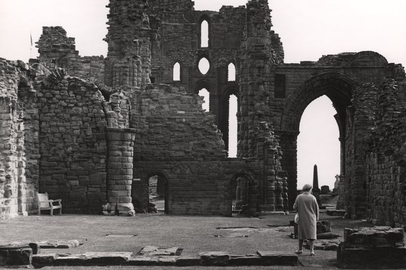 A lady in the foreground of the picture examines the ruins of Tynemouth Priory.