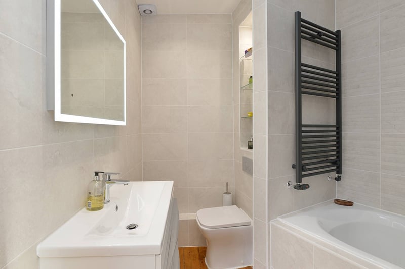 The property's bathroom, which boasts full contemporary tiling and a white suite with a mains shower over the bath.