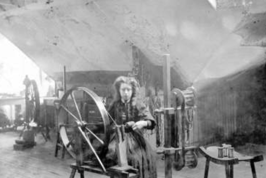 A girl winding thread from hank to bobbin in a High Street attic in the late 19th century