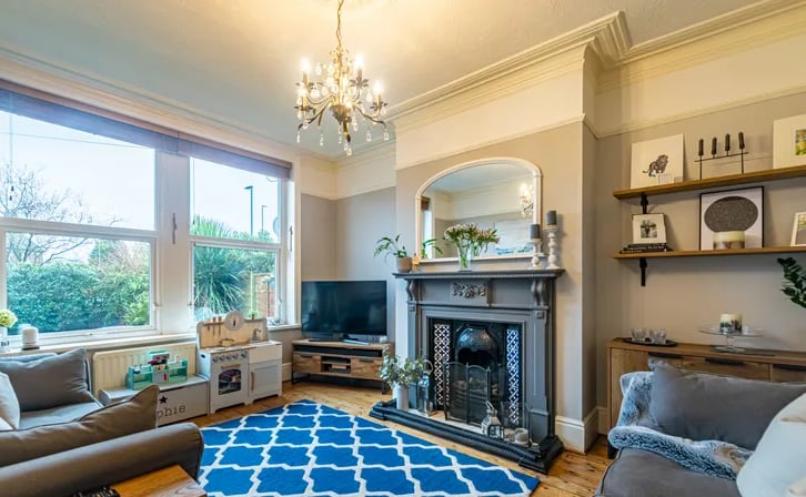 To the front is a living room with a large window, high ceilings and a period style fire surround.