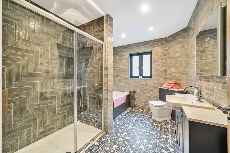 The luxurious tiled family bathroom has a bathtub and large walk-in shower.