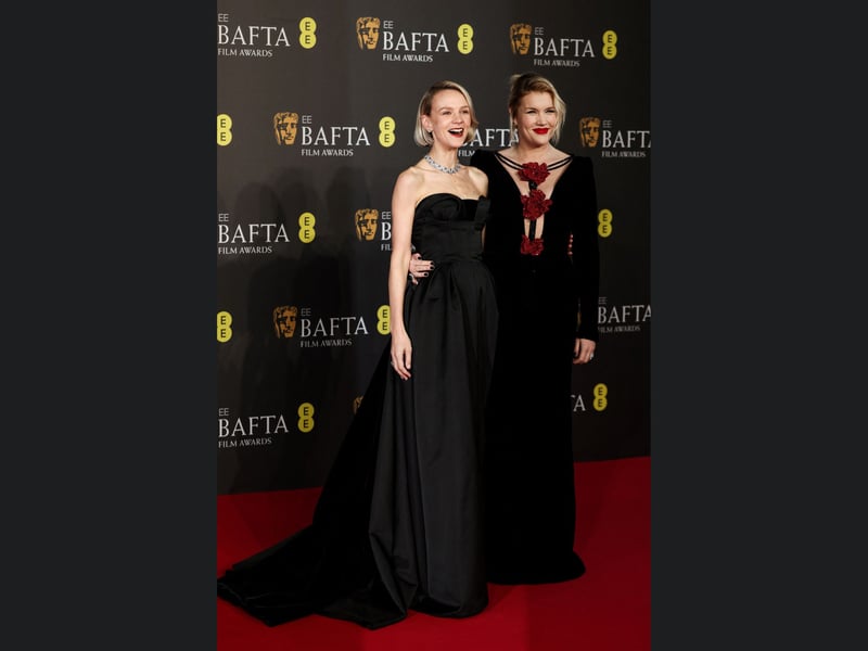 Saltburn screenwriter Emerald Fennell, right, and actress Carey Mulligan, left, pose on the red carpet upon arrival. 