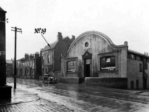 Manor Street showing houses 
 and business premises - Morris Brastoff and Sons, bristle manufacturers. To the left is Armenia Street, which is cobbled. A car is parked on Manor Street. Pictured in January 1948.