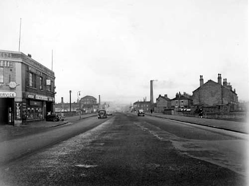 Looking north west along Sheepscar Steet South from the south end in November 1945. Whitelocks garage is visible on the corner with Benson Street. Cars and people are on the street and industrial chimneys can be seen in the background.