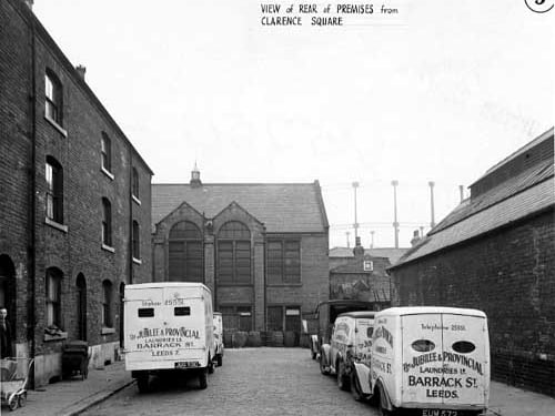 This view looks south-west down Clarence Square at the rear of Sheepscar Congregational Chapel. In the foreground are several vans from The Jubilee & Provincial Laundries Ltd., on Barrack Street. In the distance a gasholder is visible. Pictured in October 1946.