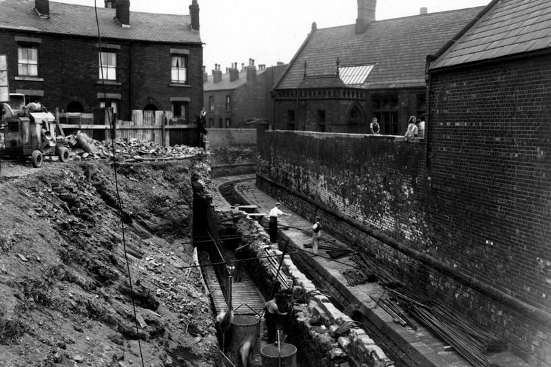 Collapsed retaining wall at Sheepscar Beck near Sheepscar Street South. The area of damage is marked with wire netting and warning lamps. Rubble can be seen in the water including large chunks of the brick wall. Pictured in July 1947.